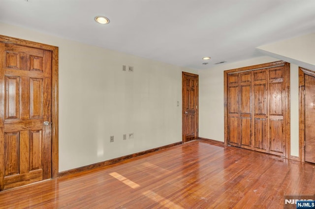 unfurnished bedroom featuring visible vents, wood finished floors, baseboards, and recessed lighting