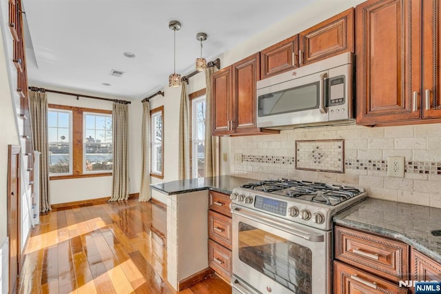 kitchen featuring plenty of natural light, baseboards, brown cabinetry, light wood-style floors, and stainless steel appliances