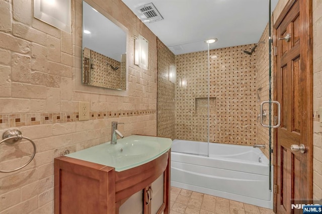 bathroom with tile walls, vanity, visible vents, and shower / bathing tub combination