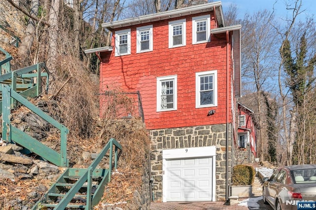 view of front facade with stone siding, a garage, and driveway