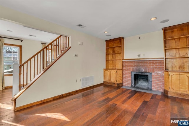unfurnished living room with baseboards, dark wood-style flooring, and visible vents