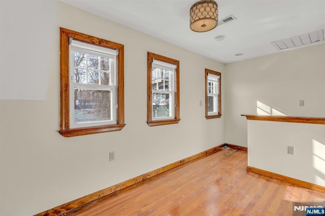 unfurnished room with baseboards, light wood finished floors, and visible vents