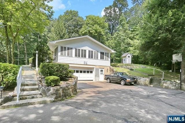 view of side of property with aphalt driveway, stairs, and an attached garage