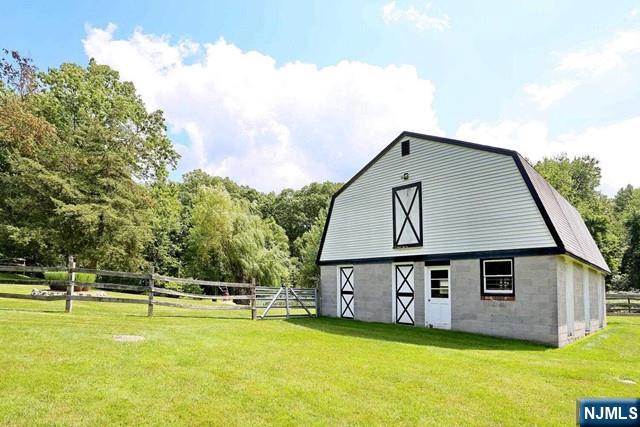 view of barn featuring a yard and fence