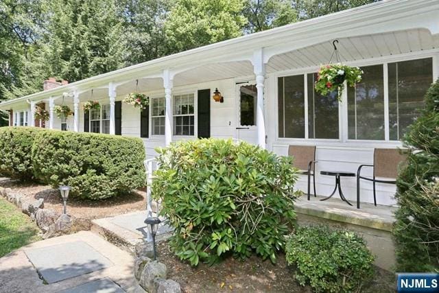 property entrance featuring a chimney and a porch