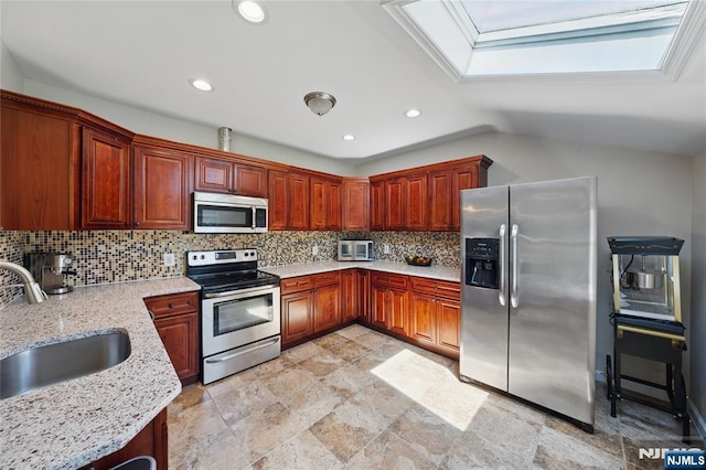 kitchen with a sink, light stone counters, stone finish floor, backsplash, and appliances with stainless steel finishes