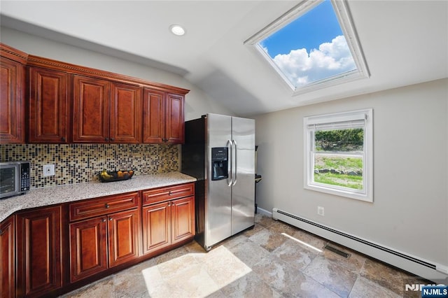 kitchen with a baseboard heating unit, stone finish flooring, stainless steel appliances, tasteful backsplash, and vaulted ceiling with skylight