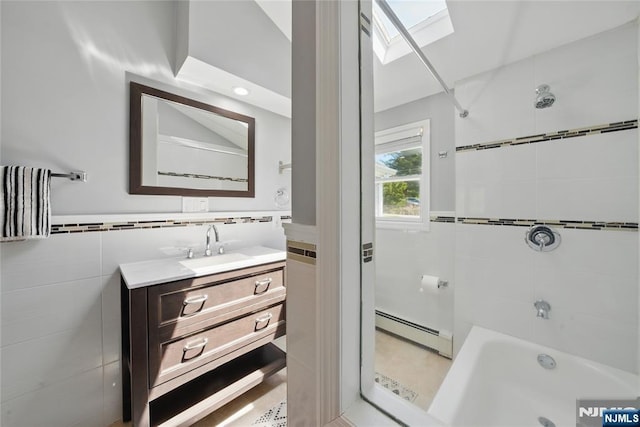 full bathroom with tile walls, a skylight, vanity, a baseboard radiator, and  shower combination