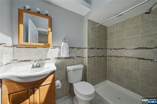 bathroom featuring vanity, toilet, tile walls, and tiled shower