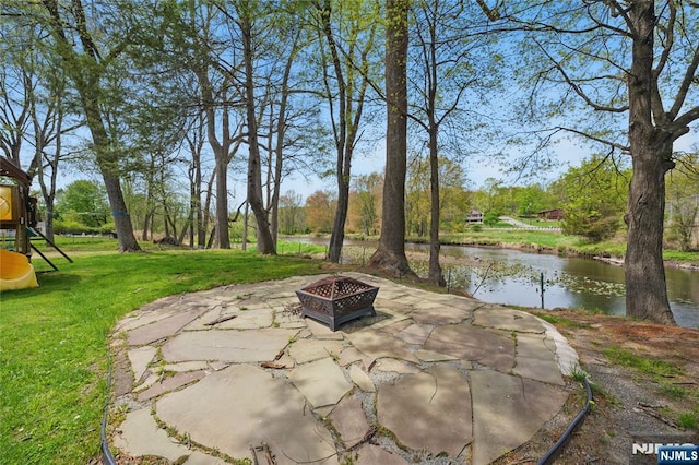 view of patio featuring a water view, a fire pit, and a playground