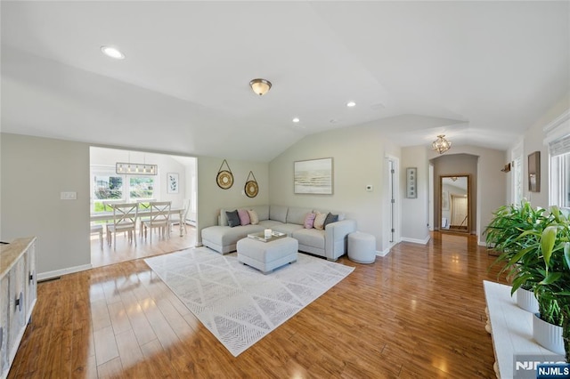 living room with an inviting chandelier, lofted ceiling, recessed lighting, and wood finished floors