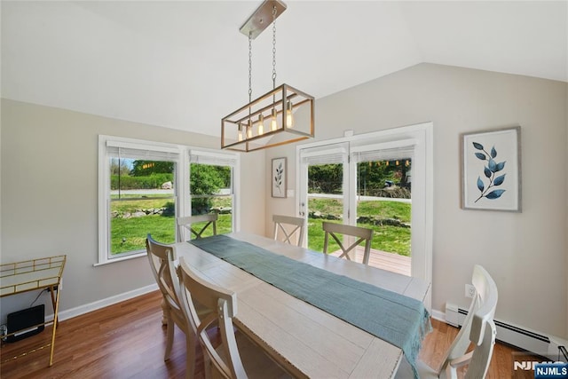 dining area with a baseboard radiator, wood finished floors, a chandelier, and vaulted ceiling