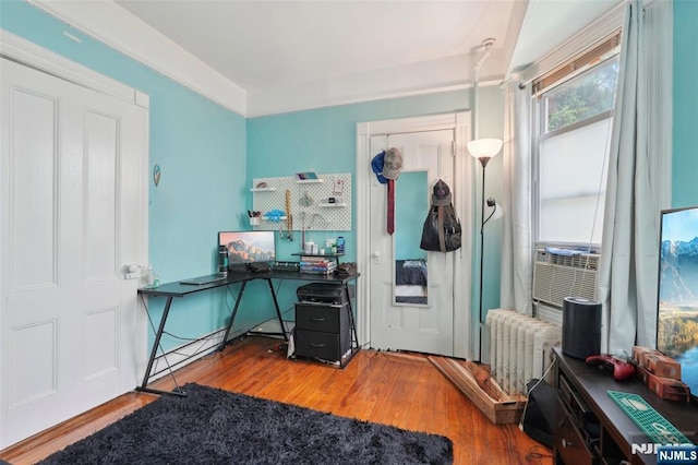 home office with radiator, wood finished floors, and cooling unit
