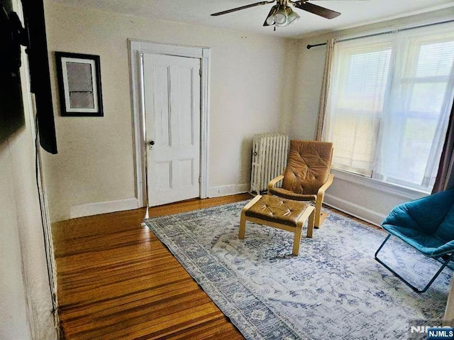 living area with radiator, ceiling fan, baseboards, and wood finished floors