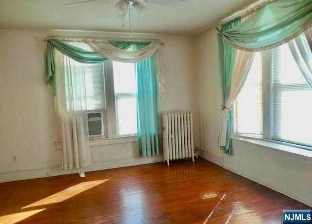 unfurnished room with radiator heating unit, a ceiling fan, and wood finished floors
