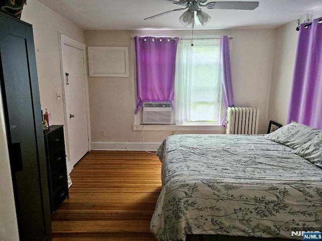 bedroom featuring radiator, wood finished floors, cooling unit, baseboards, and ceiling fan