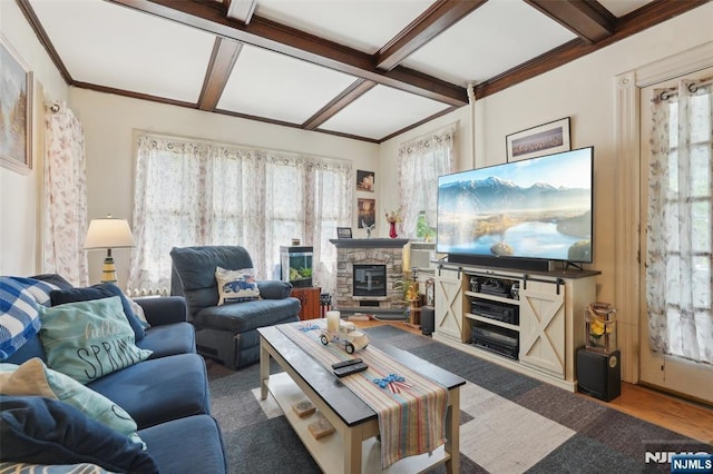 living room featuring coffered ceiling, healthy amount of natural light, beam ceiling, a stone fireplace, and wood finished floors