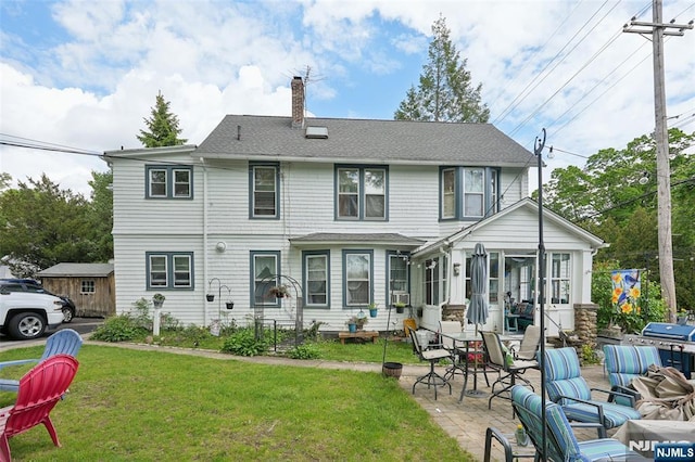 back of house featuring a chimney, a yard, a patio, and a sunroom