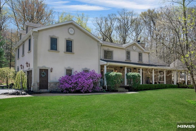 view of front of home featuring a chimney, a front yard, stucco siding, and stone siding
