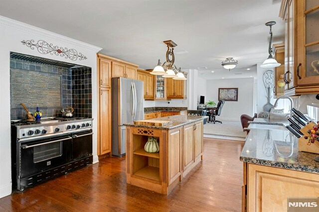 kitchen featuring dark stone countertops, freestanding refrigerator, range with two ovens, a kitchen island, and dark wood-style floors