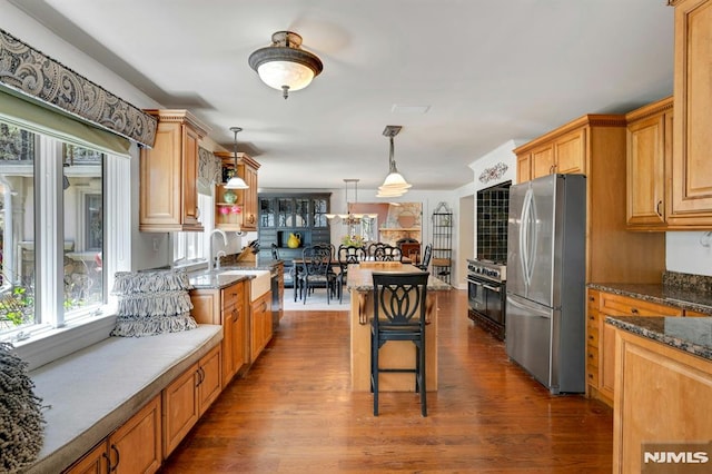 kitchen with hanging light fixtures, a kitchen bar, a sink, freestanding refrigerator, and dark wood-type flooring