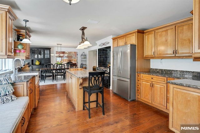 kitchen featuring a center island, freestanding refrigerator, dark stone counters, dark wood finished floors, and decorative light fixtures