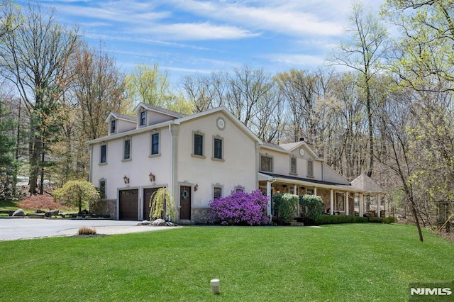 view of front facade featuring concrete driveway, stucco siding, a garage, and a front lawn
