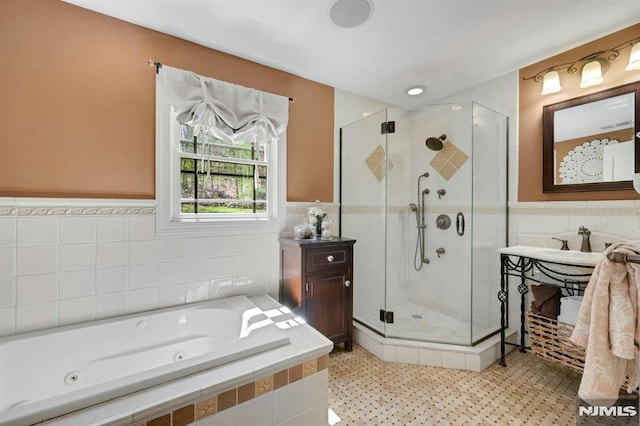 full bath featuring a stall shower, tile walls, a tub with jets, and vanity