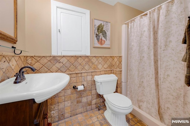 full bath featuring toilet, a shower with curtain, a wainscoted wall, tile walls, and vanity