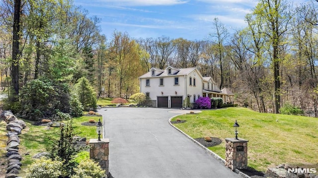 view of front facade with a garage, stucco siding, a front lawn, and driveway