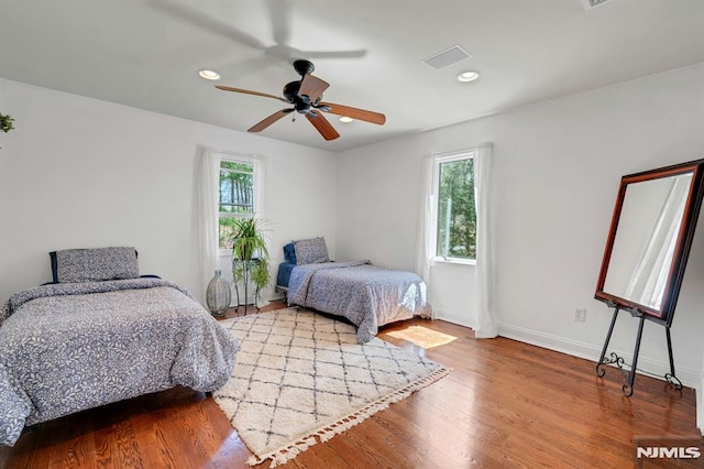 bedroom featuring wood finished floors, visible vents, recessed lighting, ceiling fan, and baseboards