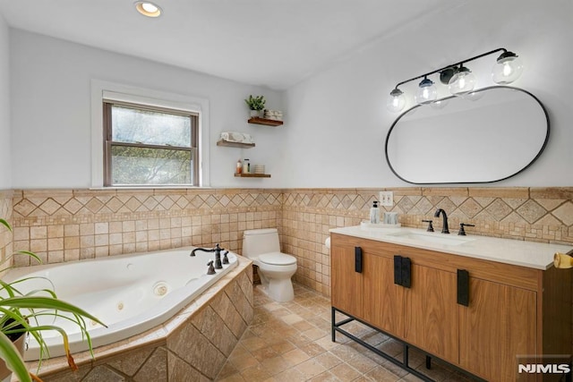 full bathroom featuring toilet, a tub with jets, wainscoting, vanity, and recessed lighting