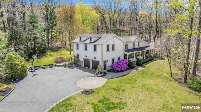 view of front of property with a chimney, driveway, an attached garage, stucco siding, and a front lawn