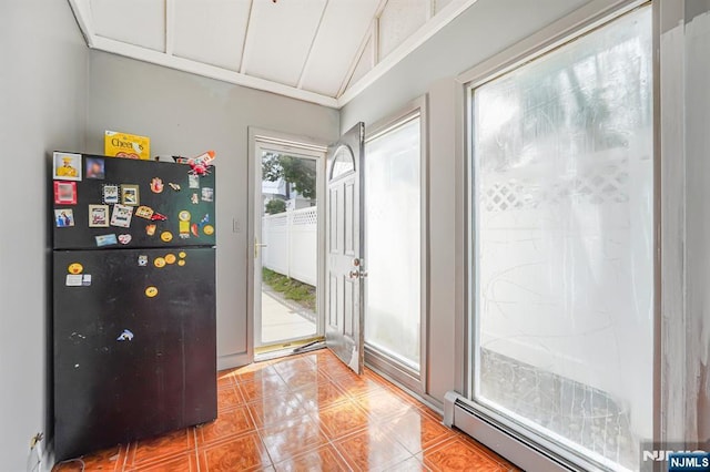 foyer featuring vaulted ceiling, light tile patterned flooring, and a baseboard heating unit