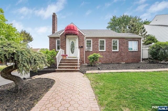 view of front of property with a front lawn, a shingled roof, brick siding, and a chimney