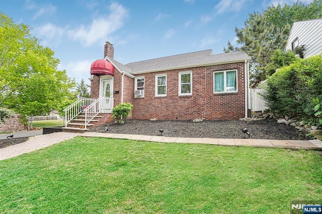 view of front of house with roof with shingles, a chimney, brick siding, and a front yard
