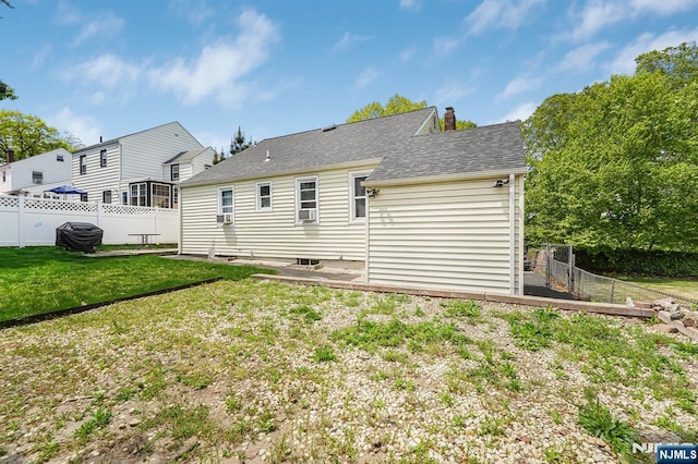 rear view of property featuring fence, roof with shingles, a chimney, and a lawn