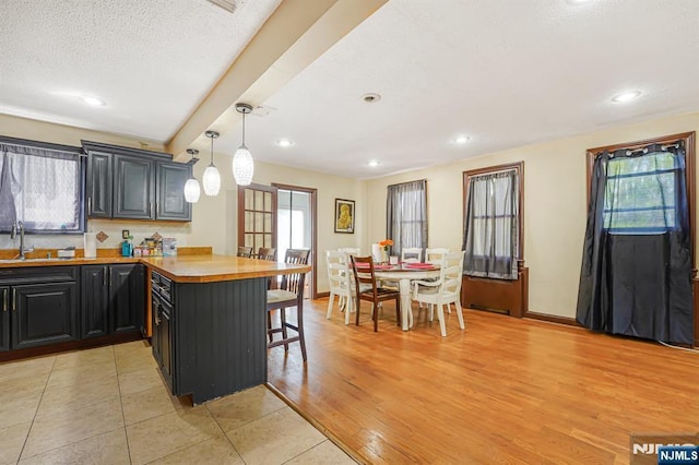 kitchen with a peninsula, a breakfast bar area, a sink, pendant lighting, and recessed lighting