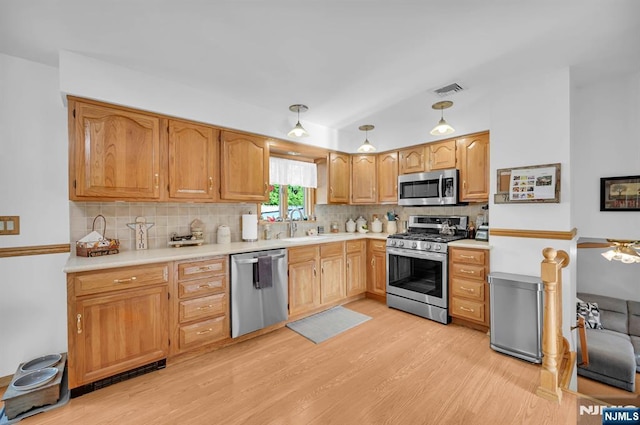kitchen with light wood-type flooring, backsplash, lofted ceiling, and appliances with stainless steel finishes