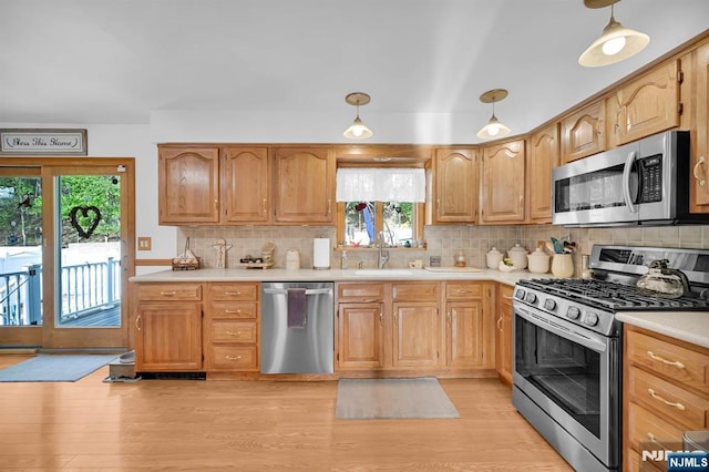 kitchen with a sink, tasteful backsplash, light countertops, and appliances with stainless steel finishes