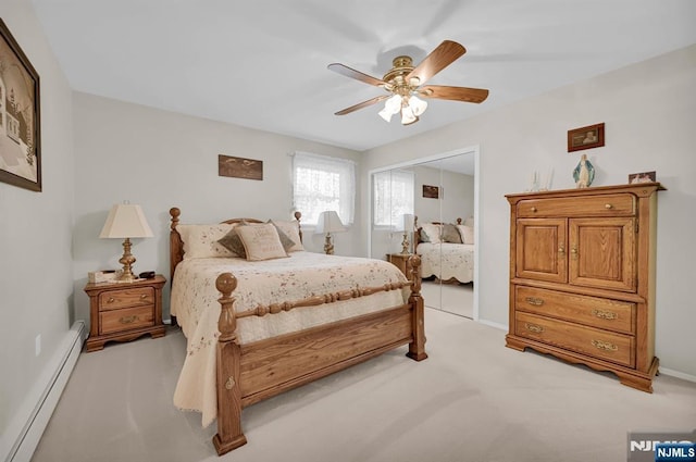 bedroom with a closet, a baseboard heating unit, light colored carpet, ceiling fan, and baseboards