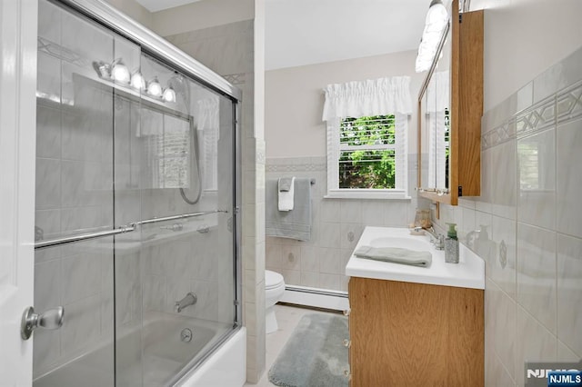 bathroom featuring tile walls, toilet, vanity, a baseboard radiator, and combined bath / shower with glass door