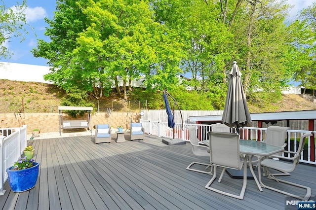 deck with outdoor dining area and a fenced backyard