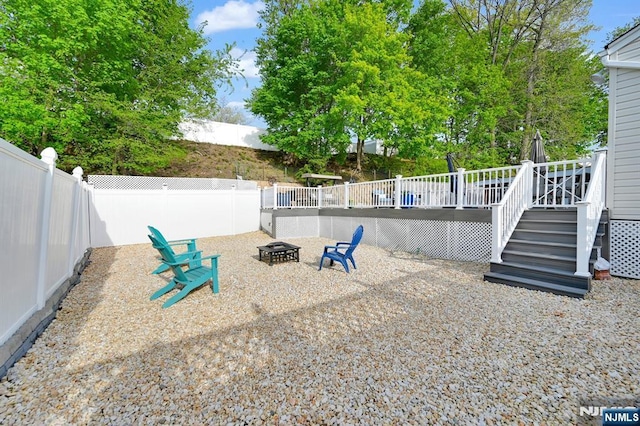 view of yard with stairway, a wooden deck, a fire pit, and a fenced backyard