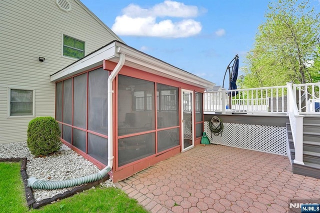 view of side of home featuring a patio area, a wooden deck, and a sunroom