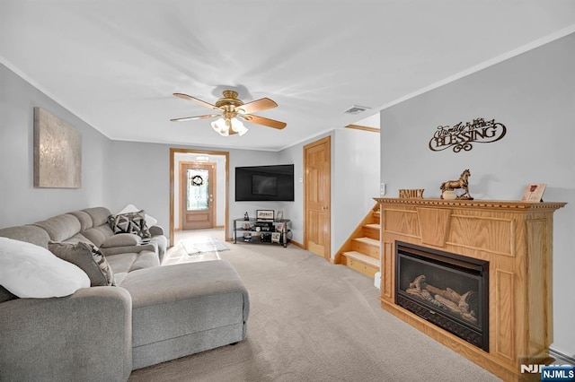 living room featuring visible vents, crown molding, light carpet, a ceiling fan, and a glass covered fireplace
