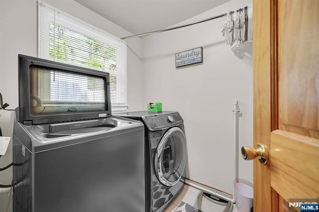 clothes washing area with washing machine and dryer, laundry area, and light tile patterned floors