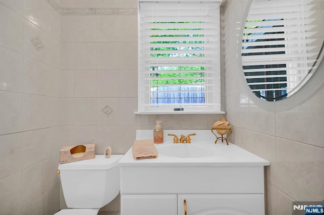 bathroom with tile walls, toilet, and vanity