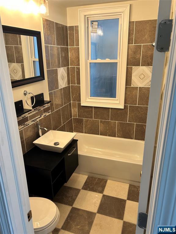 bathroom with tile walls, toilet, and a sink