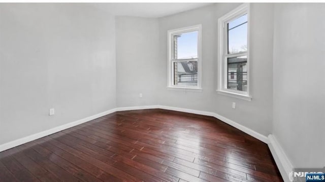 unfurnished room featuring wood-type flooring and baseboards